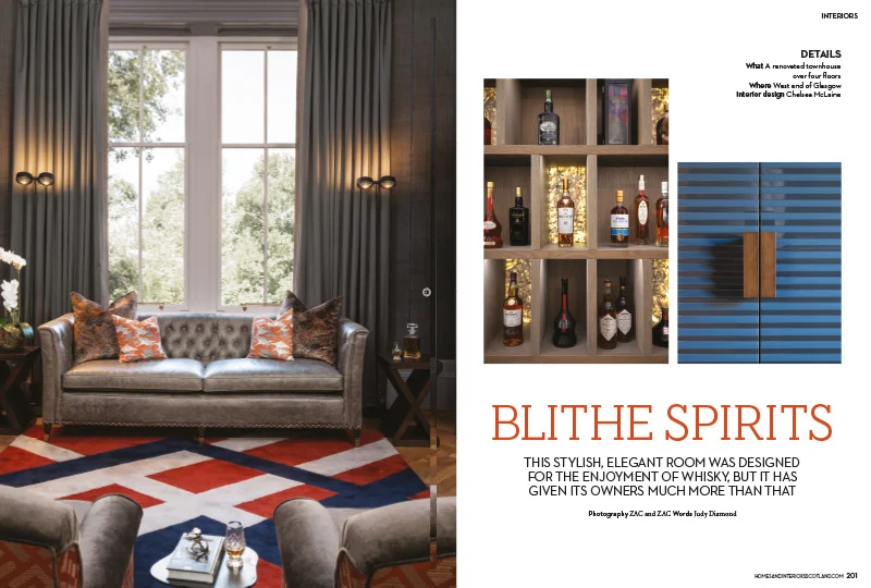 Stylish living room with grey tufted sofa, red, white & blue geometric rug, and illuminated whisky display cabinet.