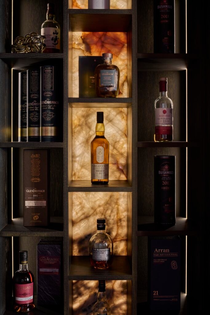 Sophisticated dark wood home bar cabinet with backlit onyx shelves displaying a collection of premium whisky.