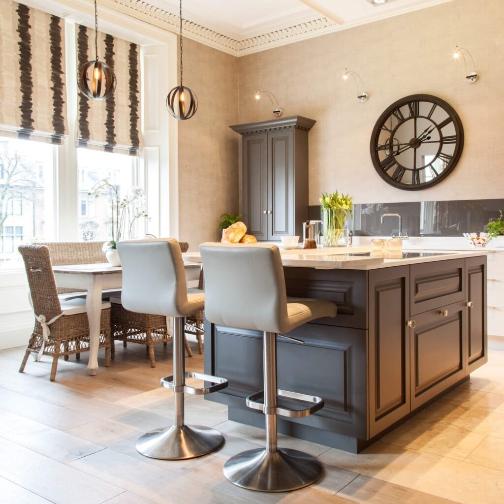 Stylish kitchen with a dark gray island, light bar stools, dining table by bright windows, and a large Roman numeral mirror clock.