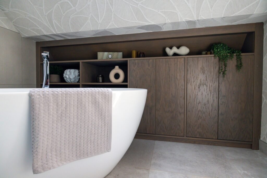 Contemporary bathroom with a white freestanding tub, dark wood cabinetry, decorative shelves, and an abstract patterned ceiling.