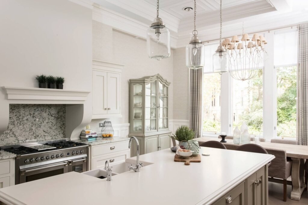 Elegant kitchen with large island, professional range, marble backsplash, display cabinet, and open dining area.