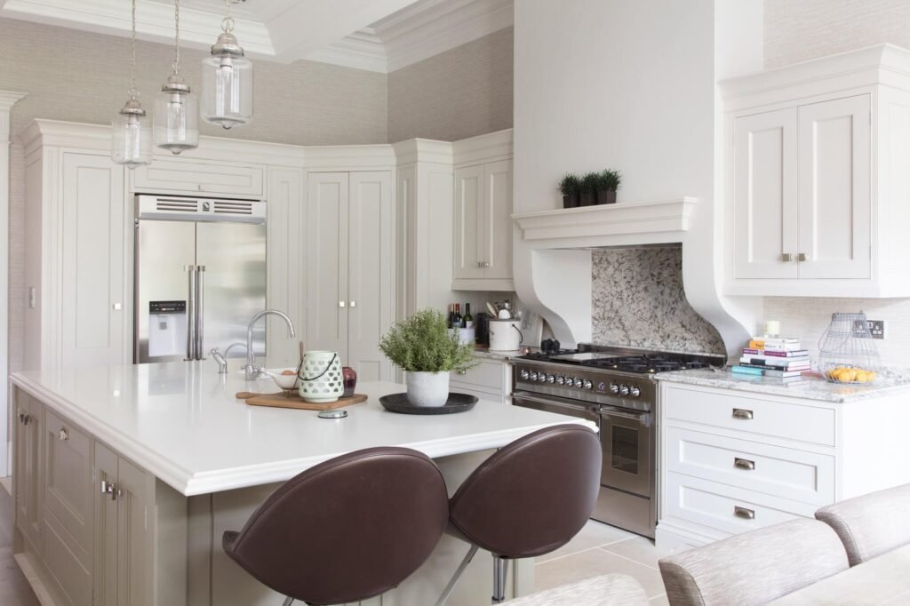 Elegant cream and white modern kitchen with a large island, stainless steel appliances, marble backsplash, and bar stools.