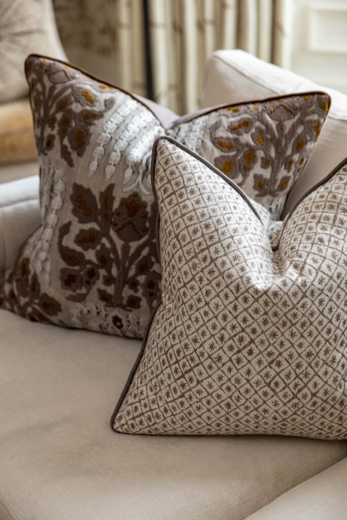 Textured brown and gold floral pillow and geometric pattern pillow on a cream sofa.