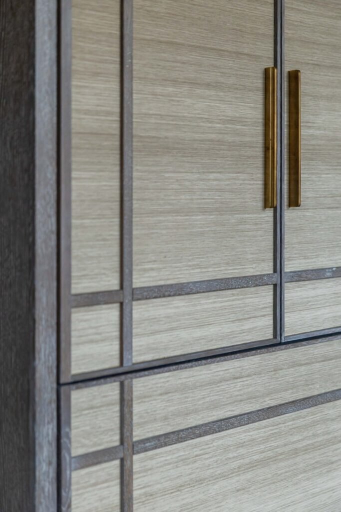Custom light wood cabinetry with dark geometric trim and sleek brass pull handles.