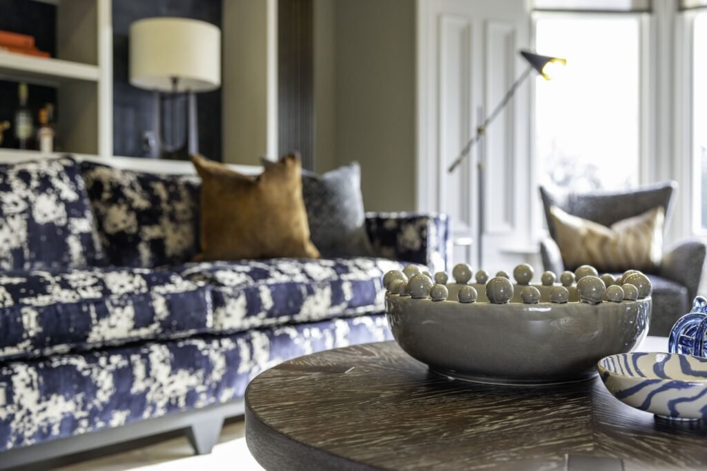 Contemporary living room with a striking blue patterned sofa, elegant decor, and ample natural light from a large window.