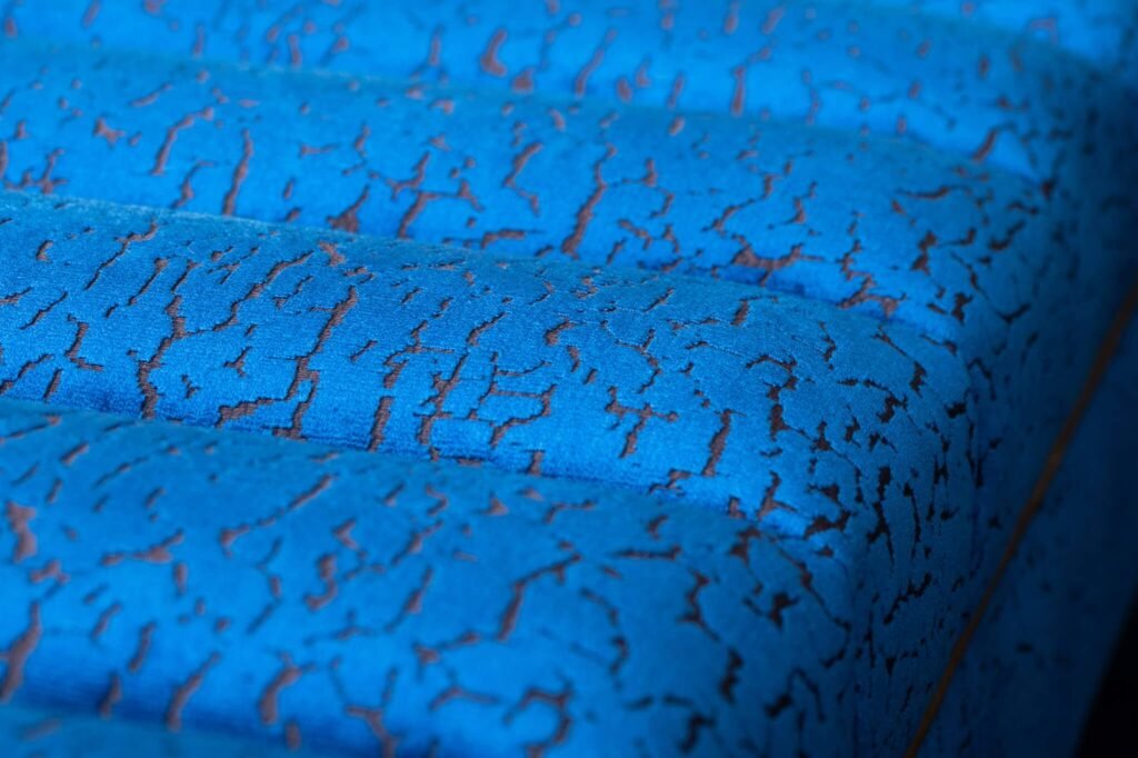 Vibrant blue upholstered fabric with a distressed brown crackle pattern and horizontal channels.