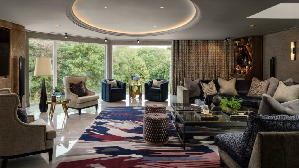 Luxurious living room with contemporary design, curved ceiling light, plush seating, colorful abstract rug, and expansive nature views.
