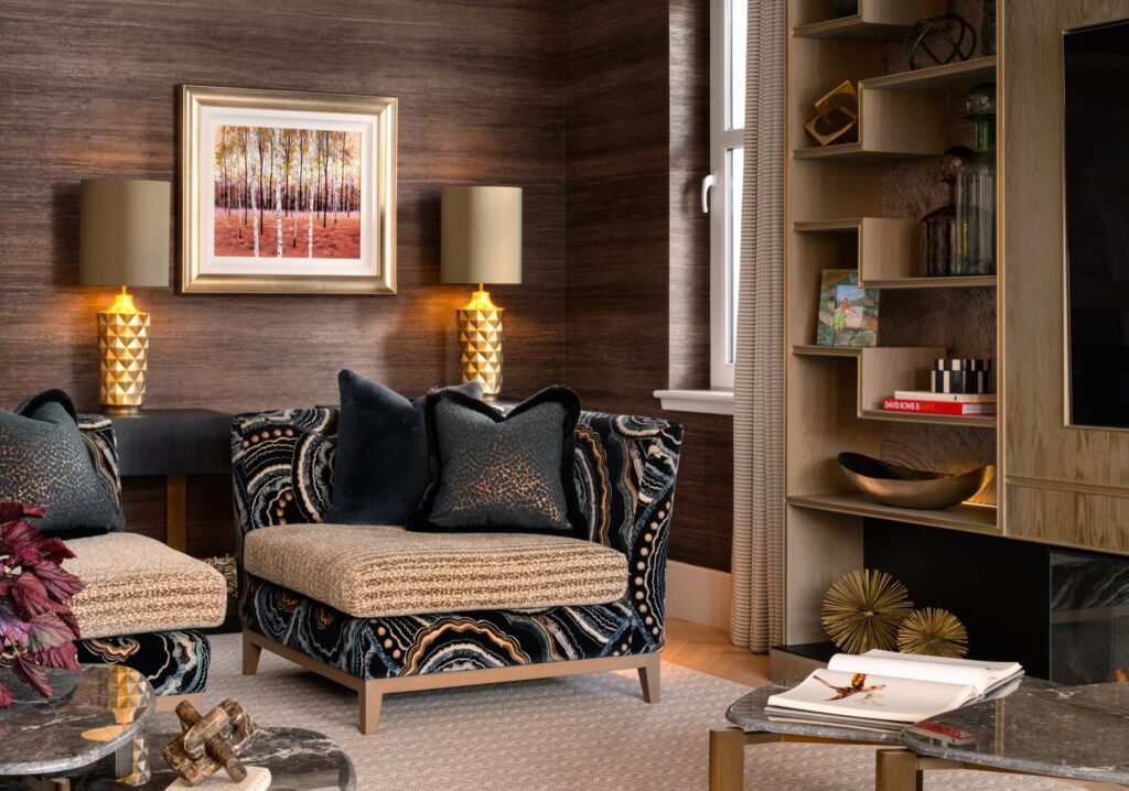 Luxurious living room with patterned armchairs, dark textured walls, gold lamps, birch art, and a light wood cabinet.
