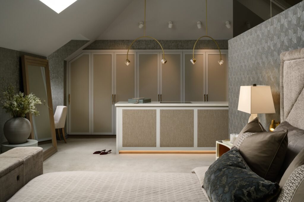 Luxury bedroom with textured built-in wardrobes, central vanity, gold pendant lights, patterned wallpaper, and plush bedding.