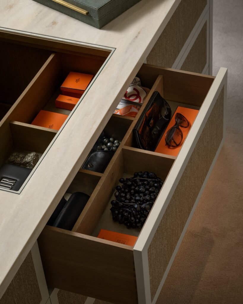 Organized luxury drawer unit with marble top, wood dividers, and designer items like Hermes boxes, Chanel scarf, and accessories.