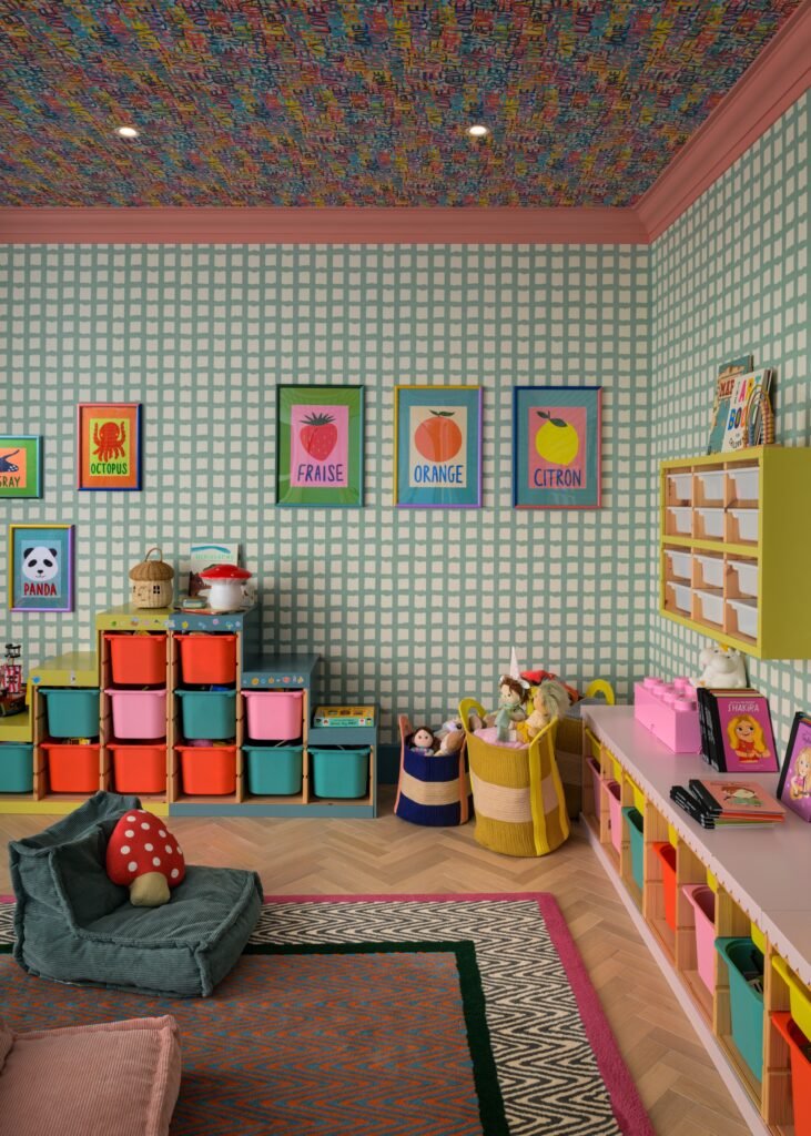 Vibrant kids' playroom with a multicolored text-patterned ceiling, grid wallpaper, colorful toy storage, and beanbag chairs.