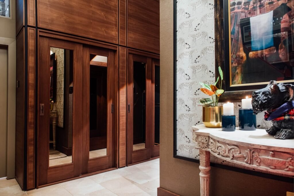 Luxury interior: custom dark wood cabinets with mirrored doors, and a carved console table with plant, candles, & dog statue.